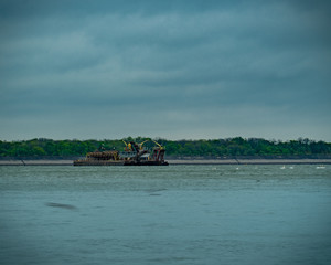 Fototapeta premium A barge in the middle of the lake on a rainy day, birds are flying around.