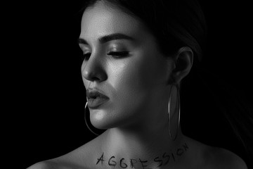black and white dramatic portrait of a young woman with the inscription aggressive on a black...