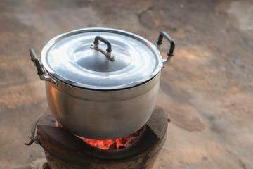 Cooking in a pot stainless steel is boiling on a charcoal stove close up.