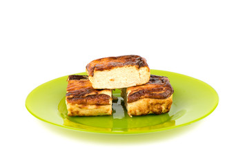 Three pieces of cottage cheese casserole on a green plate over a white background.