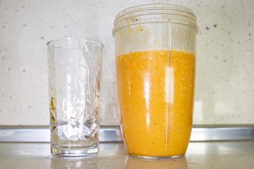 Homemade fresh orange juice in a blender and an empty glass. Close