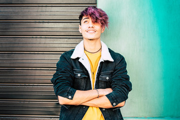 Portrait of young teenager alternative boy and colorful clothes and wall background - urban people...