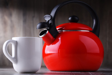 Cup of coffee and stainless steel stovetop kettle with whistle