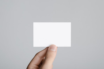 Fototapeta premium Business Card Mock-Up (85x55mm) - Male hands holding a blank card on a gray background.