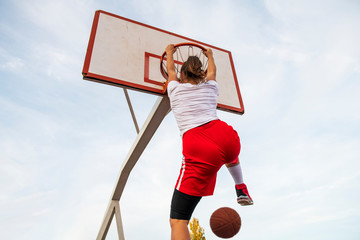 Females playing basketball on street court. Woman streetball player making slam dunk in a basketball game. © FS-Stock
