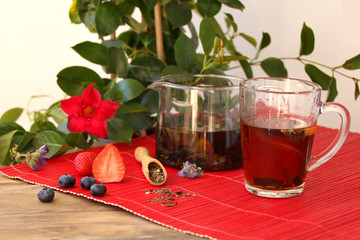teapot with tea leaves, herbal tea, in the background fruits, dry fruit, berries, flowers, the...