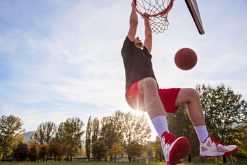 Young man jumping and making a fantastic slam dunk playing streetball, basketball. Urban authentic. © FS-Stock