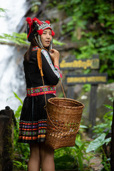Portrait of Asia hmong lady holding basket and standing near waterfall in hill tribe