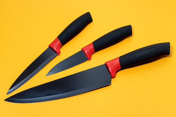 Set kitchen knives with a black handle on yellow background