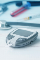 Digital glucometer and lancet pen, stethoscope, blood in vitro, on white background. Diabetes managemen