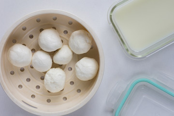 Top view of fresh homemade mozzarella balls on strainer close to whey to store cheese