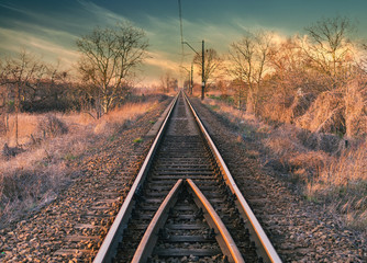 Fototapeta premium Railway line straight to the beautiful sunset