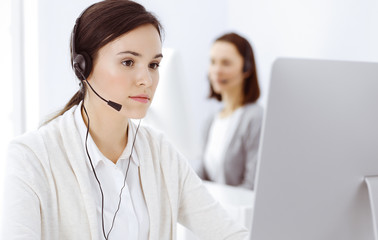 Call center. Casual dressed woman sitting in headset at customer service office. Group of operators...