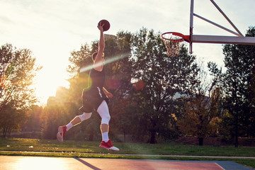 Young man jumping and making a fantastic slam dunk playing streetball, basketball. Urban authentic. © FS-Stock