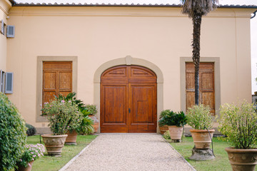 Large arched wooden door in the facade of the building of an old villa-winery.