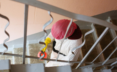 Woman in protective medical mask and suit while disinfection of residential house in Moscow. Housing and communal services work during covid-19/ coronavirus pandemic in Russia. Quarantine life.  