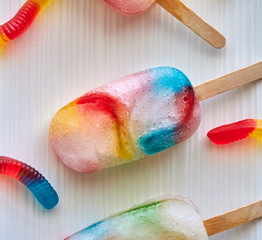 Top view of colorful frozen gummy worm popsicles on a white plate, great for kids in the summer...