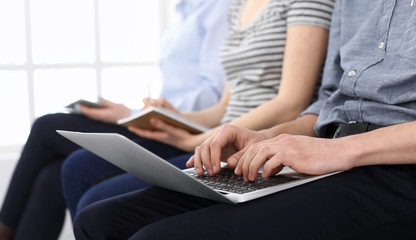 Fototapeta premium Group of casual dressed business people working at meeting or conference, close-up of hands. Businessman using laptop computer. Teamwork or coaching concept