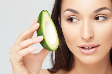 Young beautiful woman with avocado closeup