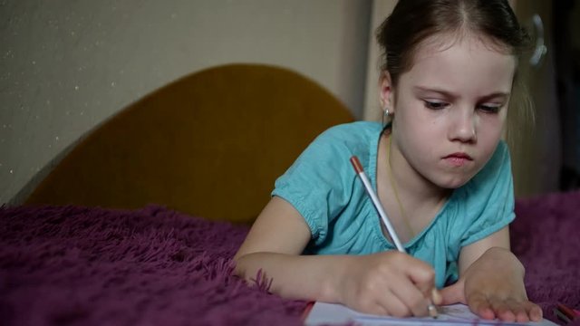 Cute little girl draws with pencils a postcard for for dad on father's day.