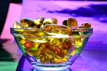 omega 3 capsule. In a glass bowl on a colored background.