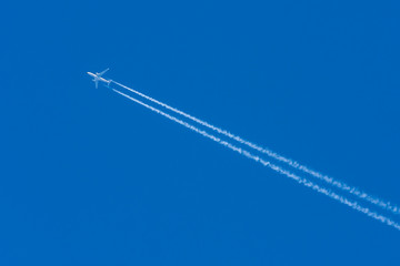 Silhouette of an airplane in the blue sky without clouds.