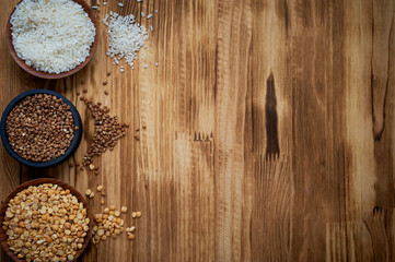 Useful food. The evils and the legumes. Buckwheat, rice, peas in flats on a wooden background. Simple and healthy food.