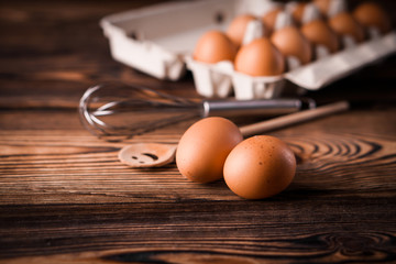 Detail close-up of chicken eggs in egg box on the old brown wooden background.