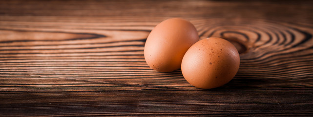 Banner detail close-up of chicken eggs on the old brown wooden background.