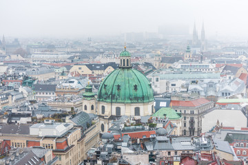 Obraz na płótnie Canvas Cityscape of Vienna with Peterkirche (St. Peter's church) in a snowy day, in the old town of Vienna, Austria. View at the tower of St. Stephen's Cathedral.