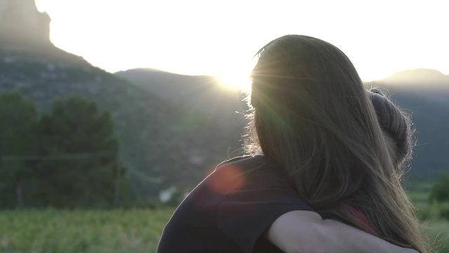Lesbian girls couple hugging and kissing under the sunset.
