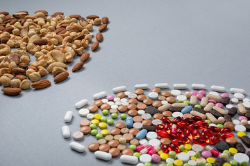 Healthy lifestyle concept. Pills and types of roasted nuts on gray background. Immunity and healthy fats for beauty