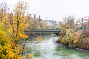 Fototapeta na wymiar Landscape with buildings and yellow trees and bridge at the riverbank of Donaukanal (Danube cannal) in a rainy day, , in Vienna, Austria.