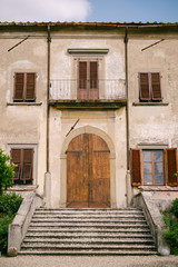 Fototapeta na wymiar Facade of an old villa in Italy, in Florence. Stone stairs, wooden door, windows with wooden shutters.