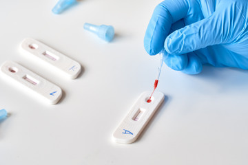 Rapid COVID19 test for detection of specific antibodies IgM and IgG to novel corona virus SARS-CoV-2 causing Covid-19 illness. Medic or doctor applies blood from patient finger on test..