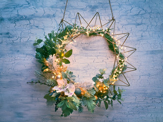 Decorative Christmas wreath with fir, winter leaves and flowers on geometric golden metal frame...