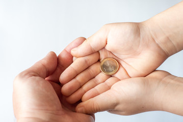 Concept of donations, saving, or pocket money. Little child with coins and father hand, closeup.