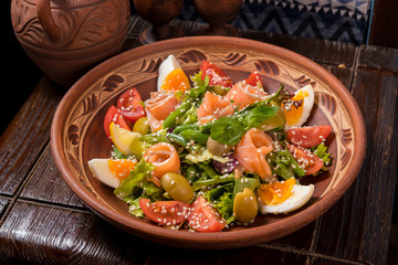 Hospitable Georgian cuisine. Salad with salmon, egg, tomatoes and arugula
