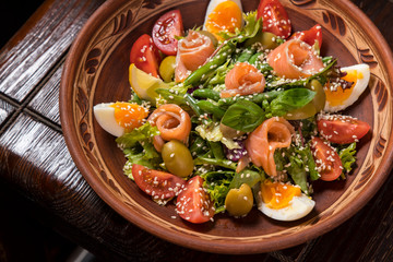 Hospitable Georgian cuisine. Salad with salmon, egg, tomatoes and arugula
