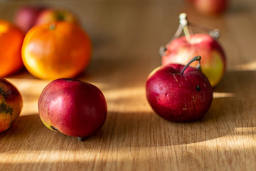 Bright juicy fruits, natural and natural fruits with damage. Red apples and tangerines on a modern brown light table