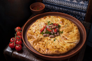 Hospitable Georgian cuisine. Khachapuri with beans on a wooden background
