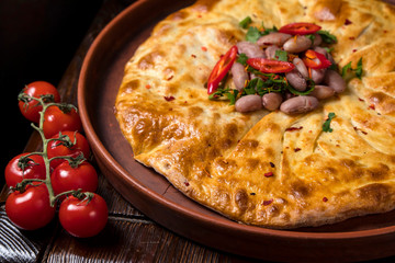 Hospitable Georgian cuisine. Khachapuri with beans on a wooden background
