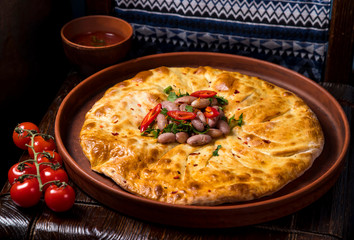 Hospitable Georgian cuisine. Khachapuri with beans on a wooden background
