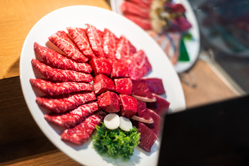 Closeup of plate display outside restaurant with cuts of red raw meat kobe or wagyu beef behind glass window in Tokyo
