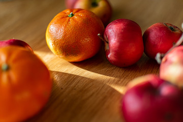 Bright juicy fruits, natural and natural fruits with damage. Red apples and tangerines on a modern brown light table