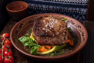 grilled steak with greens in a round ethnic plate. Georgian cuisine