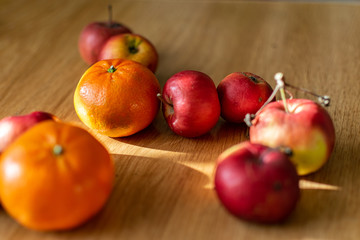 Naklejka na ściany i meble Bright juicy fruits, natural and natural fruits with damage. Red apples and tangerines on a modern brown light table