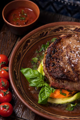 grilled steak with greens in a round ethnic plate. Georgian cuisine