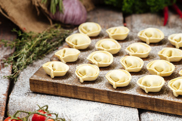 Semi-finished pelmeni dumplings on wooden board
