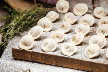 Semi-finished pelmeni dumplings on wooden board